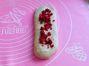 取一块松弛好的面团，再次擀长舌状，平铺上蔓越莓干。