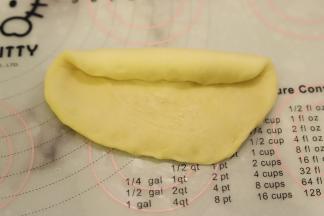 取一小块面团，擀成圆形，翻面，从上往下卷。