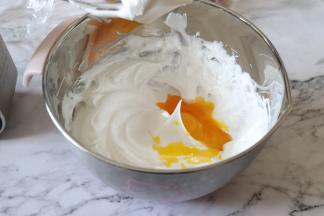 打发到蛋白拉起打蛋器，呈现比较尖的角，也就是蛋白是硬性发泡阶段。之后倒入全部的蛋黄。用电动打蛋器，把蛋黄搅匀。