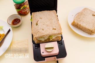 放一层生菜，再盖一片吐司，用手按压一下吐司，合上盖子，扣好卡扣。