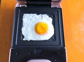 轻食机预热3分钟，刷上食用油，打入一个鸡蛋，盖上盖子煎1分钟