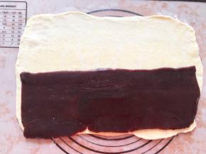 最后再次擀成长方形，豆沙放入保鲜袋中擀成长方形，放在面团上