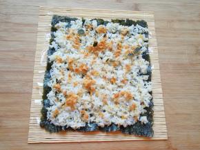 用勺子将米饭均匀的铺在紫菜上面，撒上肉松。