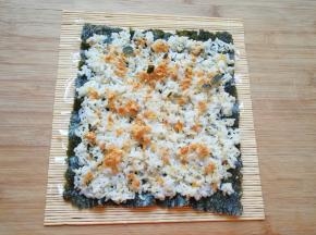 用勺子将米饭均匀的铺在紫菜上面，撒上肉松。