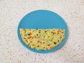 取一个盘子，从中间的二分之一处铺上米饭，用勺子把边缘压整齐。