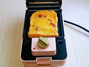 三明治机器连接电源预热1分钟，烤盘上刷少许食用油，再放上裹好蛋液的吐司片。