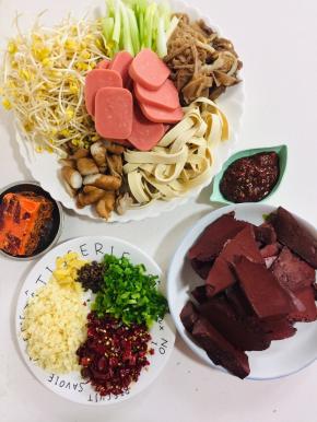 首先准备好这道菜所需要的食材：

猪血切成块儿，黄豆芽洗净，千张切成条状，卤肥肠切成段，毛肚切条，芹菜切成段，火腿肠切成片，蒜瓣切成末，葱切成葱花，干辣椒切成段，准备好一块火锅底料，花椒和一勺郫县豆瓣酱备用！

