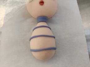 如图用蓝色的面团搓细长条，做出身体来，脖子那里的擀薄片，切一个宽条就可以