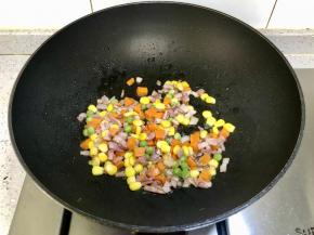 接着下入什锦蔬菜粒翻炒。