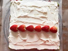 蛋糕做好以后趁热撕掉油纸，温热后切掉四边，抹上奶油，中间放上草莓