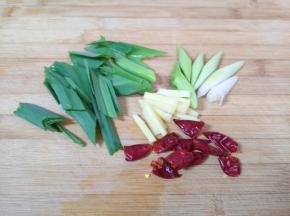 蒜苗洗干净切成段，叶子和蒜白部分分开，生姜切成丝，干红辣椒掰成两半。