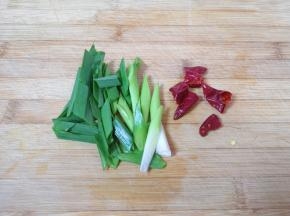 蒜苗洗干净切成段，干红辣椒掰成两半。