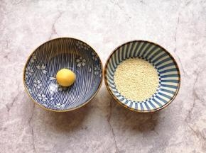 准备两个小碗，一个小碗底放上一点点水，一个小碗里放上熟白芝麻，先把南瓜糯米球放进有水的小碗里沾上水。