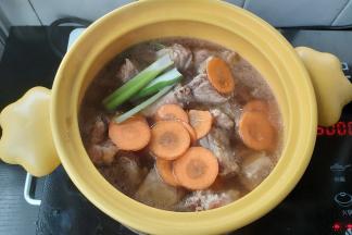 在排骨上面放上葱段、胡萝卜片，大火煮至汤水沸腾。