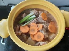 在排骨上面放上葱段、胡萝卜片，大火煮至汤水沸腾。