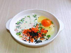鸡蛋磕盘里。加入胡萝卜碎，葱花，熟黑芝麻，牛奶，用筷子打散至均匀。