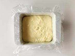 取一个方形模具，铺上保鲜膜，方便脱模。把熬好的奶糊倒进去，刮平。