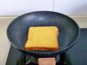 平底锅中刷少许食用油，放上裹满蛋液的吐司片，小火煎。