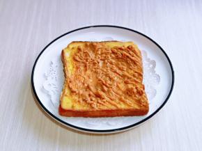 取一片吐司放在盘中，均匀涂抹上花生酱。