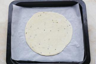 手抓饼平铺到铺上油纸的烤盘中。