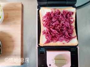 三明治机先预热3分钟，在煎盘上刷一点点植物油，不要多，一点点就OK。先放一片白吐司，再放一层红椰菜，红椰菜是可以直接吃的。