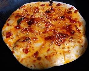 不粘锅滴少许底油加热放入饼中火煎两面金黄色涂抹上炒好的酱料撒上芝麻