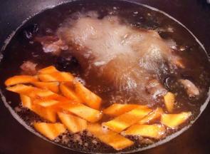胡萝卜切片和泡发好的木耳以及调味料蚝油、一品鲜酱油、糖放入汤中烧开