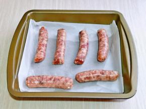 首先将牛肉肠摆放在垫有油纸的烤盘中。