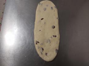 取出一个松弛好的面团，用擀面杖轻轻地自中间分别向上向下擀开，成长条状。