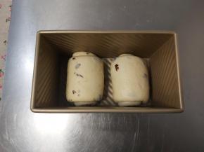 把卷好的面团放入吐司盒，收口位置朝下，然后放入烤箱进行二次发酵，烤箱内准备一碗热水，创造一个相对湿润的发酵环境。