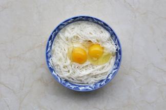 剩面条放入大碗中，打入两个鸡蛋。