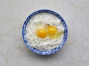 剩面条放入大碗中，打入两个鸡蛋。