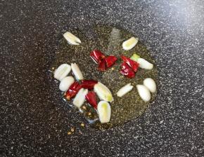 炒锅内倒入适量的食用油烧热，下入蒜片和干红辣椒炒香。