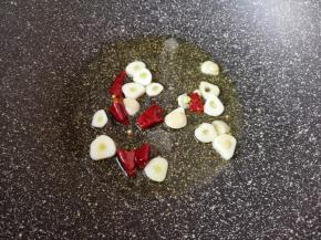 炒锅内倒适量的食用油烧热，下入蒜片和干红辣椒炒出香味。