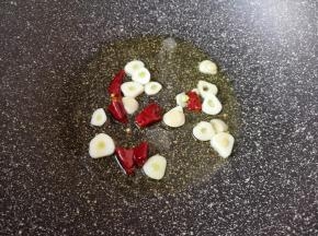 炒锅内倒适量的食用油烧热，下入蒜片和干红辣椒炒出香味。