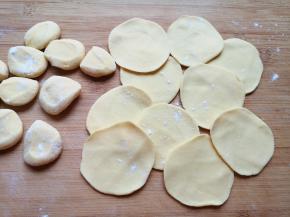 将小剂子压扁，擀成中间稍厚边缘薄的饺子皮。