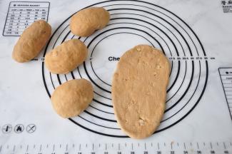 取一个小面团光面朝上，压扁，然后从中间向上向下擀开，翻面再翻转。