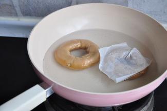 将整形好的面团放入垫了油纸的烤盘上，放入温暖处发酵30分钟左右。在发酵过程中将1000毫升的水和50克的糖放在锅中煮至微沸，转小火，同时预热烤箱。将面团放入水中，发酵成功的面团应立即浮起来。顺势撕去底部了的油纸。