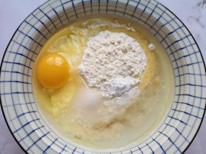 面粉中打入一个鸡蛋，加入盐、玉米油、泡打粉和温水。