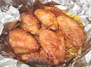 5 烤盘上铺上一层锡纸，码上腌好的鸡翅，连同腌料一起放入。把烤盘放在空气炸锅的高烤架上