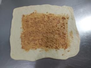 取出一块松弛好的面团，用擀面杖擀成正方形，把花生酱在中间抹个正方形。