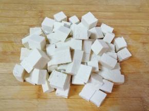 老豆腐冲洗一下，用厨房用纸吸干表面的水分，切成2厘米大小的方块。