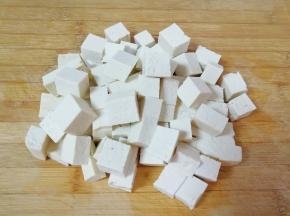 老豆腐冲洗一下，用厨房用纸吸干表面的水分，切成2厘米大小的方块。