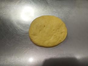 取一个松弛好的面团，收口朝上拍扁，包入一个30g的豆沙馅。