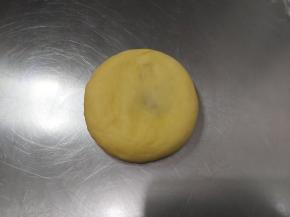 取出一块包好豆沙的面团，收口朝下压扁，擀成长舌状。