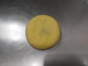 取出一块包好豆沙的面团，收口朝下压扁，擀成长舌状。