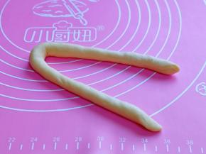 取一块面团，搓成长条，再对折，如图。