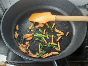 接着刚才的油锅，倒入胡萝卜丝、葱段，中小火煎炸出香味。