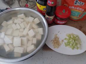 首先准备好全部需要的食材配料，豆腐切大块用盐水浸泡，生姜切末，小葱切小段。