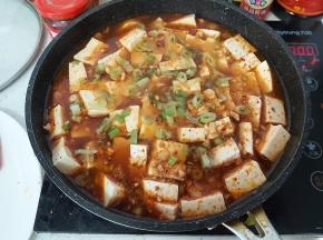 然后把捣碎的花生碎、葱花，撒在豆腐上，转中小火，盖盖子焖炖十分钟左右。